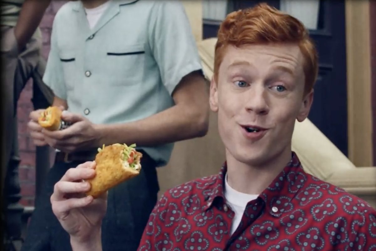 Kevin grinning mid-bite, holding up a taco